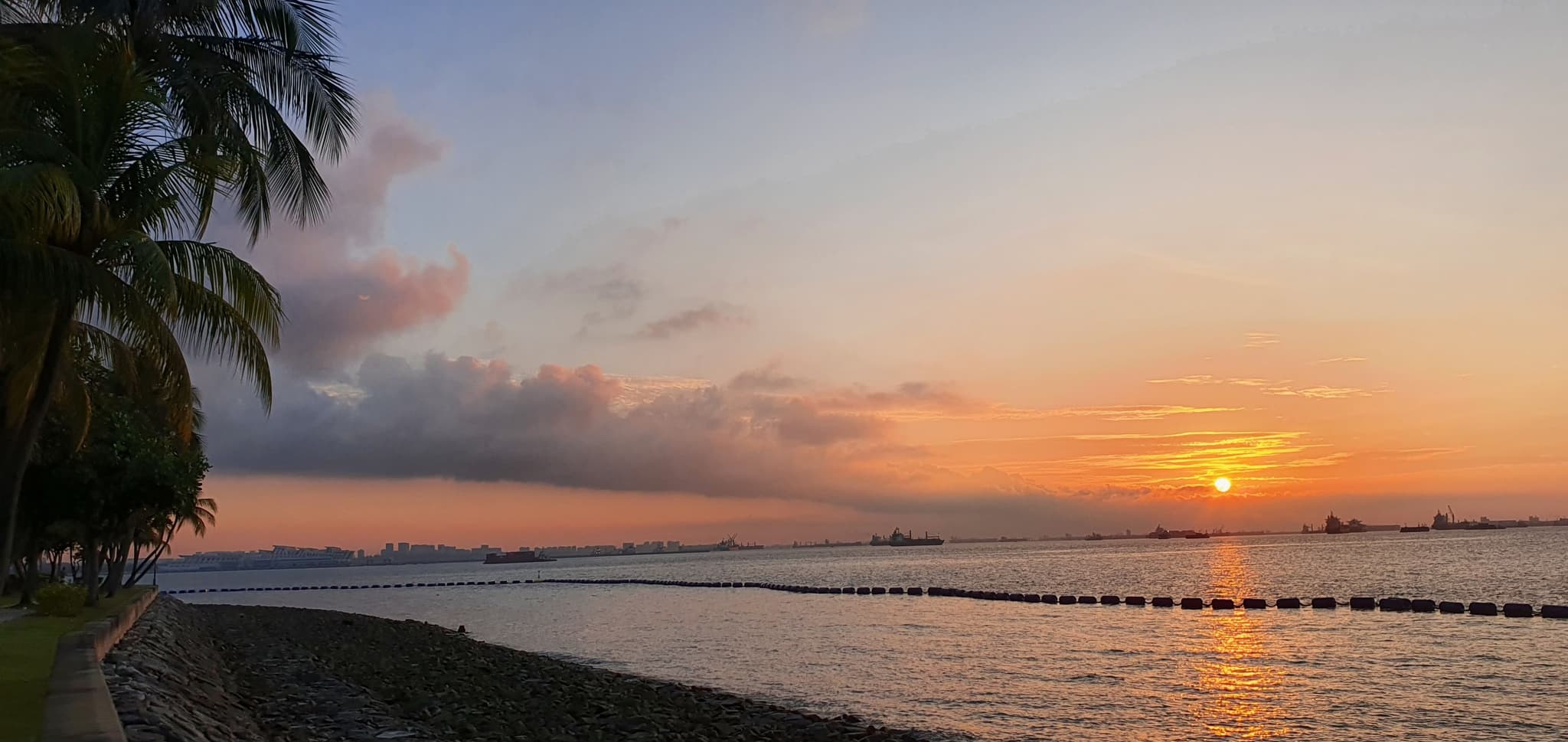 Climate Resilience - Coastal sunset with tropical environment and distant port infrastructure